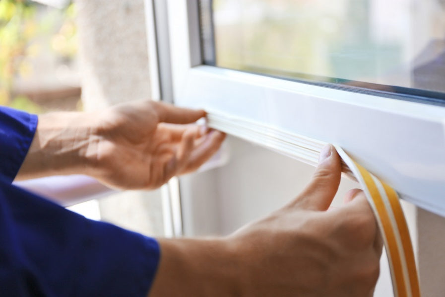 Person applying weatherstripping to window